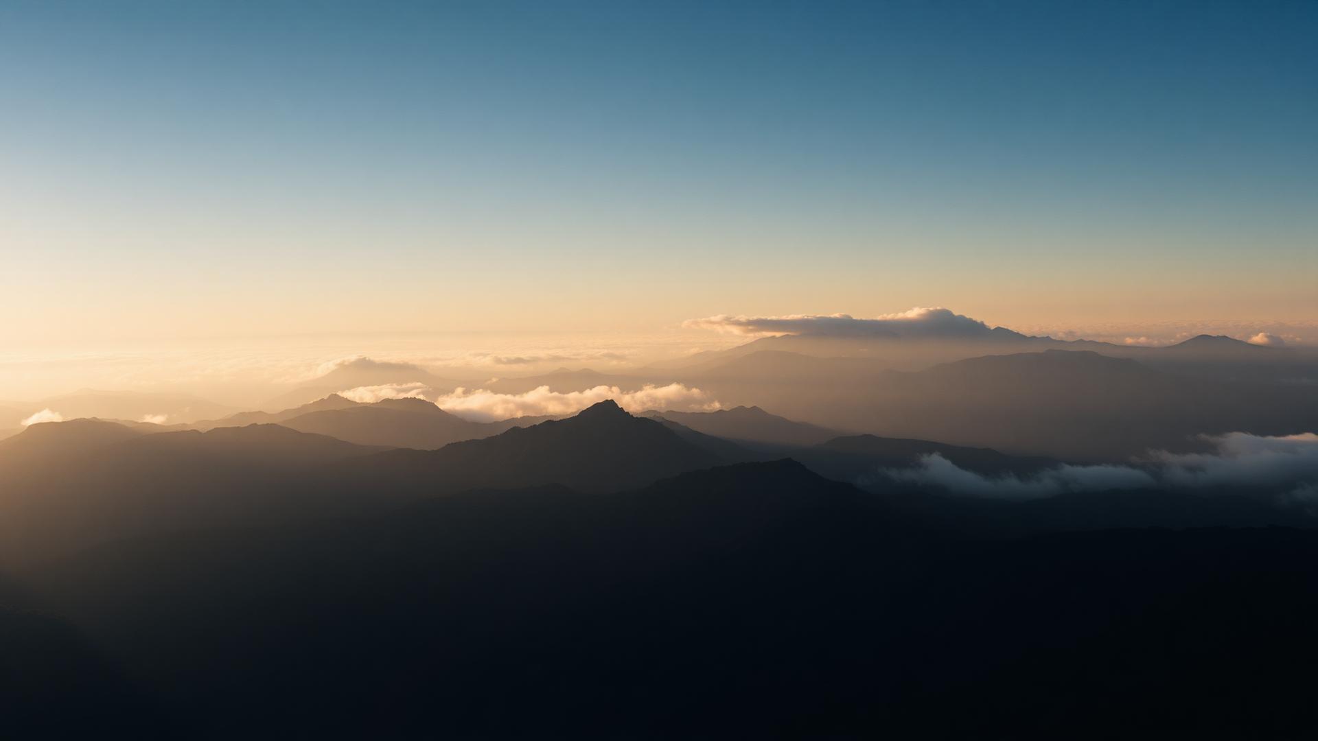 Layered mountain ridges rising above the cloud line